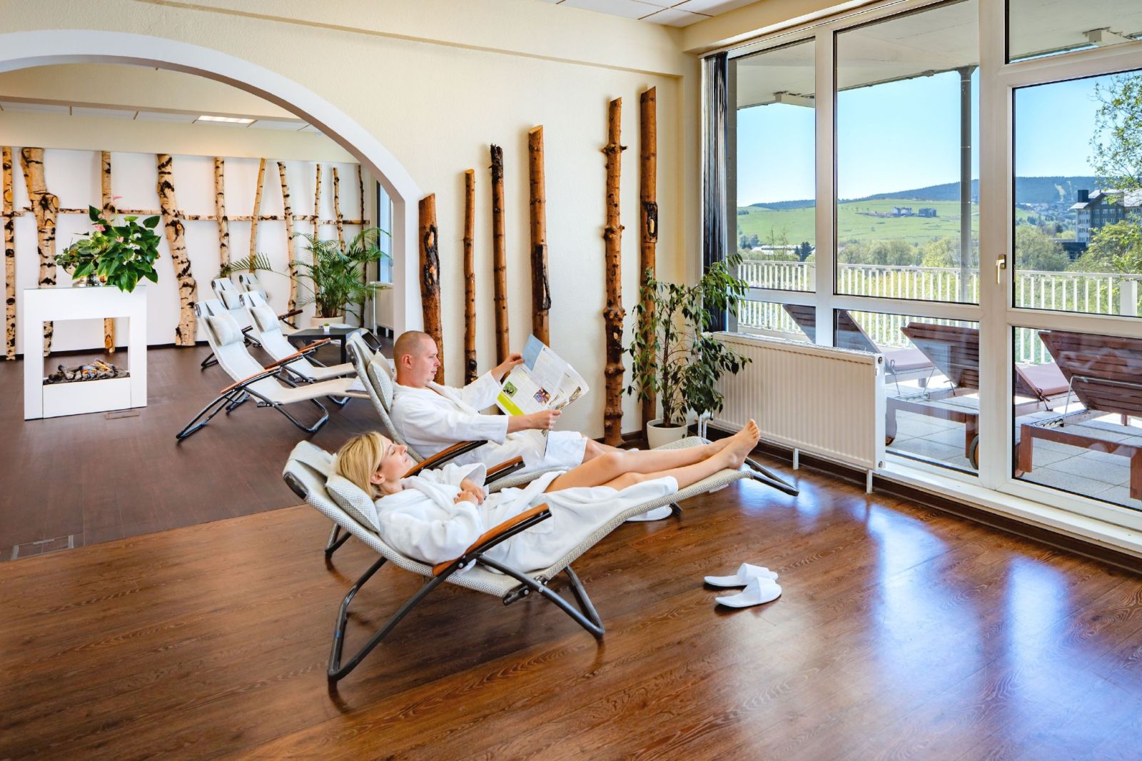 Sauna area in light colors with wooden elements and loungers on which two people can relax